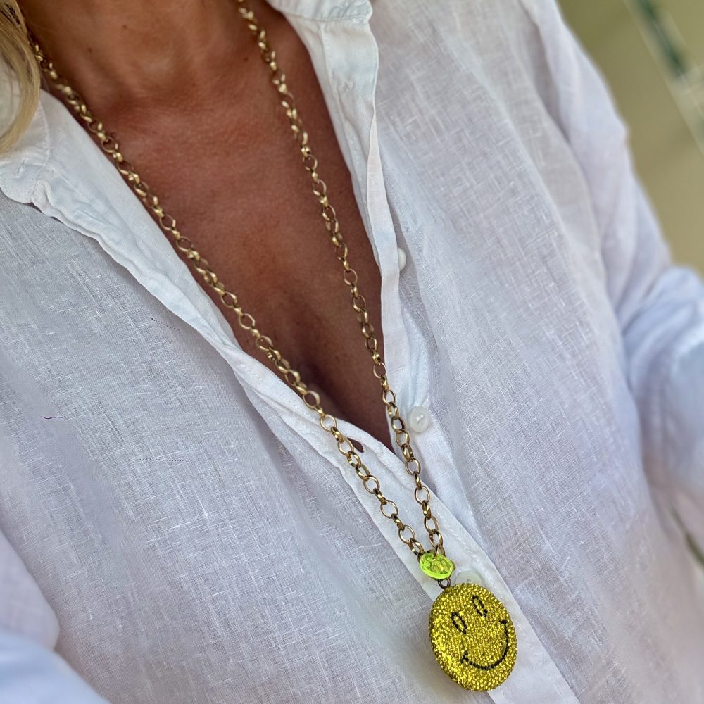 Sautoir Smiley Seventy-three, un bijou étincelant avec ses strass brillants, son sourire malicieux, et la chaine en acier inoxydable.