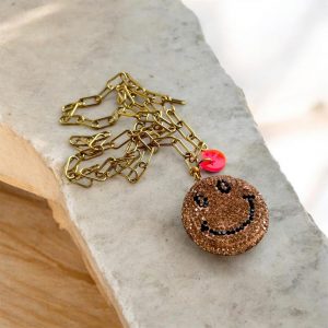 Sautoir Smiley Seventy-three, un bijou étincelant avec ses strass brillants, son sourire malicieux, et la chaine en acier inoxydable.