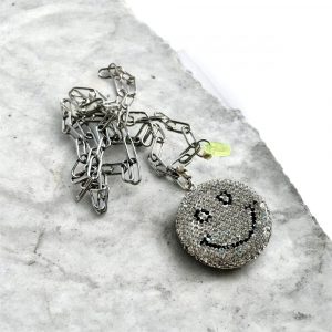 Sautoir Smiley Seventy-three, un bijou étincelant avec ses strass brillants, son sourire malicieux, et la chaine en acier inoxydable.