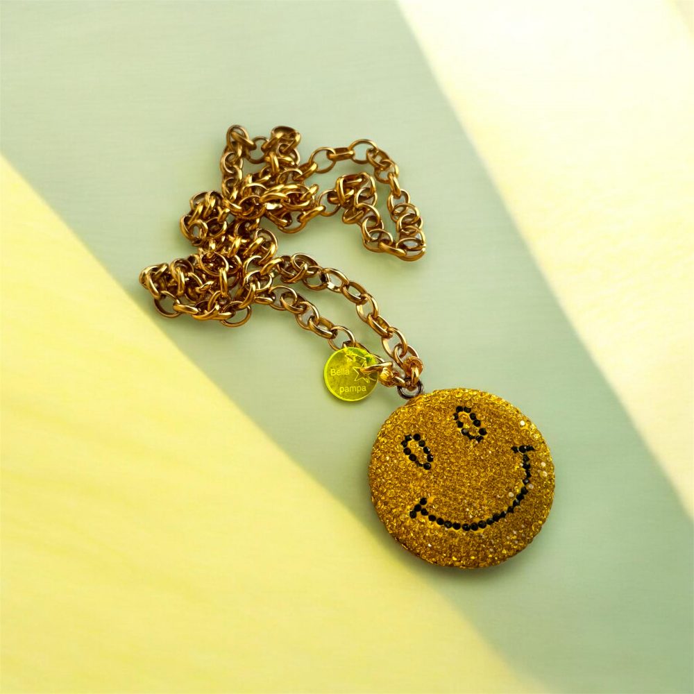 Sautoir Smiley Seventy-three, un bijou étincelant avec ses strass brillants, son sourire malicieux, et la chaine en acier inoxydable.